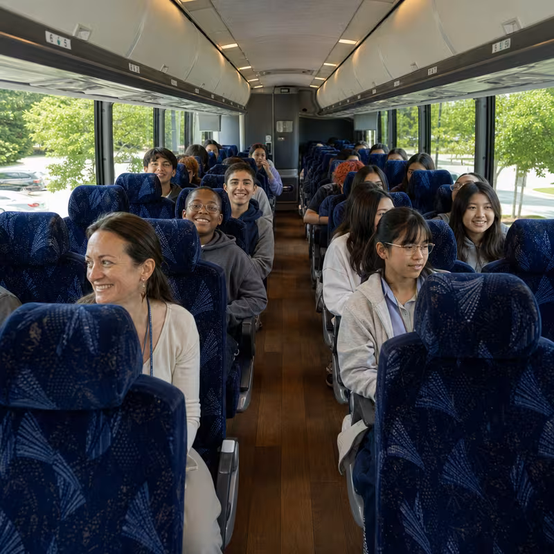Group boarding a white charter bus for School Transportation transportation in Davie